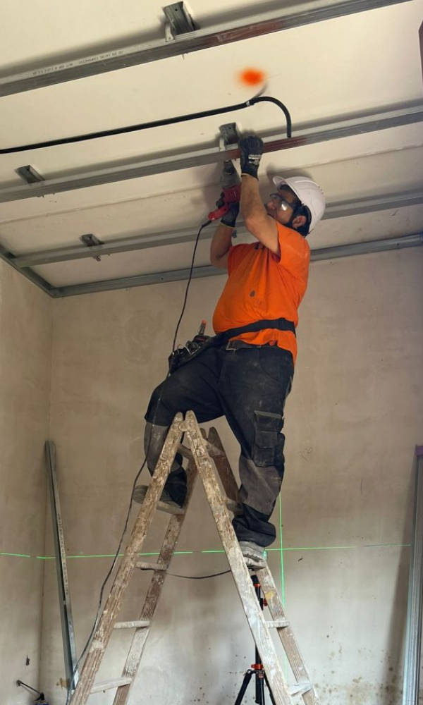 Técnico instalando estructura de techo de pladur con perfiles metálicos en obra.